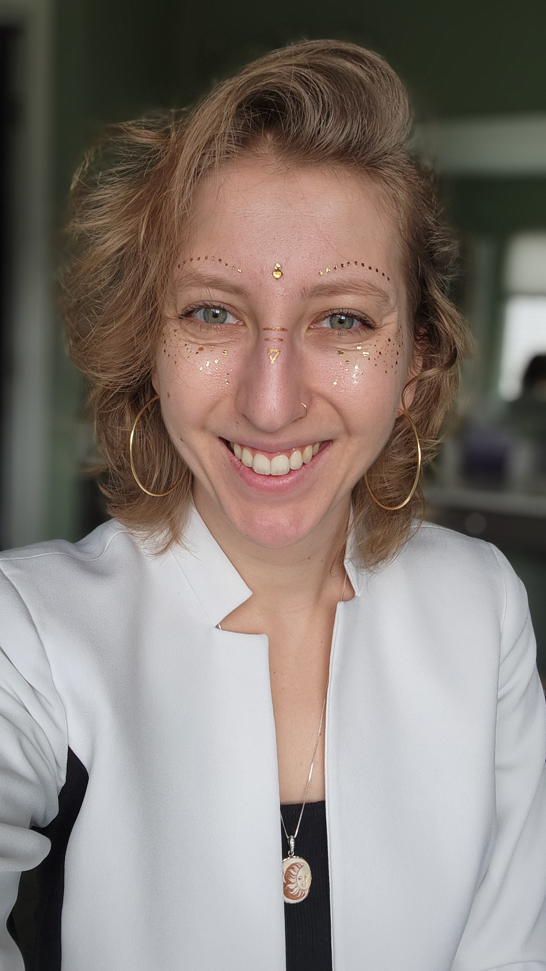 Shaman Lady Lighthouse smiling with gold hoop earrings and gold accents on her face